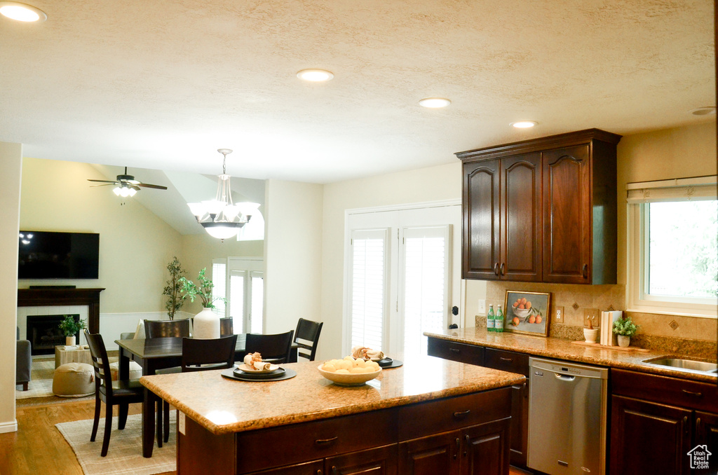 Kitchen with light wood finished floors, dishwasher, a fireplace, a ceiling fan, and decorative light fixtures