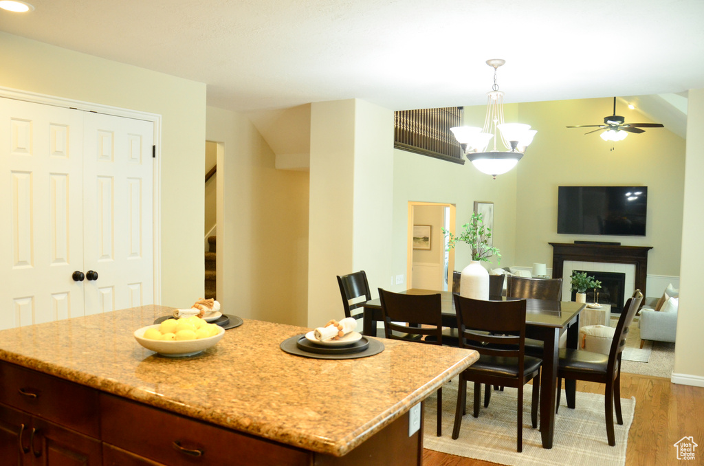 Kitchen with hanging light fixtures, light wood-style floors, a fireplace, and light stone counters