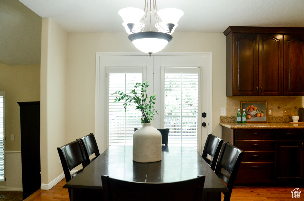 Dining area featuring baseboards, wood finished floors, and a chandelier