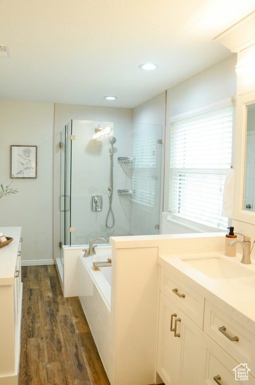 Full bath featuring a stall shower, vanity, a garden tub, wood finished floors, and recessed lighting