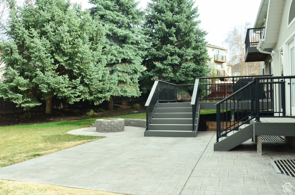 View of patio with an outdoor fire pit, a deck, and stairs