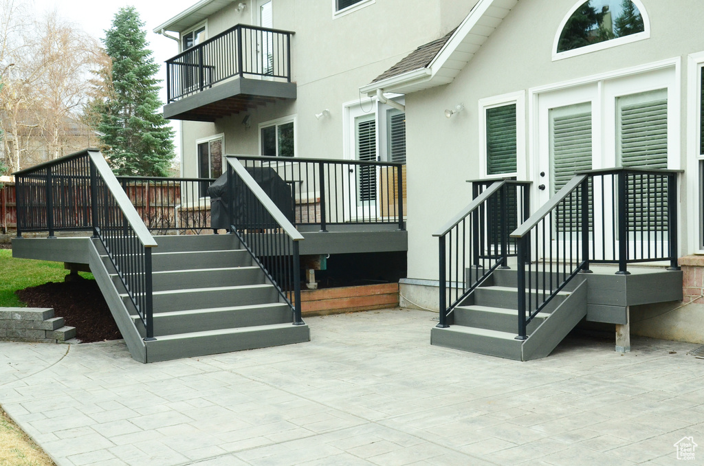 Exterior space with a balcony, stucco siding, and a patio area