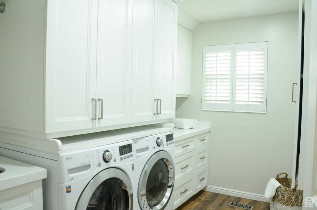 Laundry room featuring washing machine and dryer, dark wood-style floors, baseboards, visible vents, and cabinet space