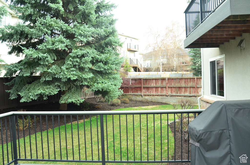 View of yard featuring a balcony and a fenced backyard
