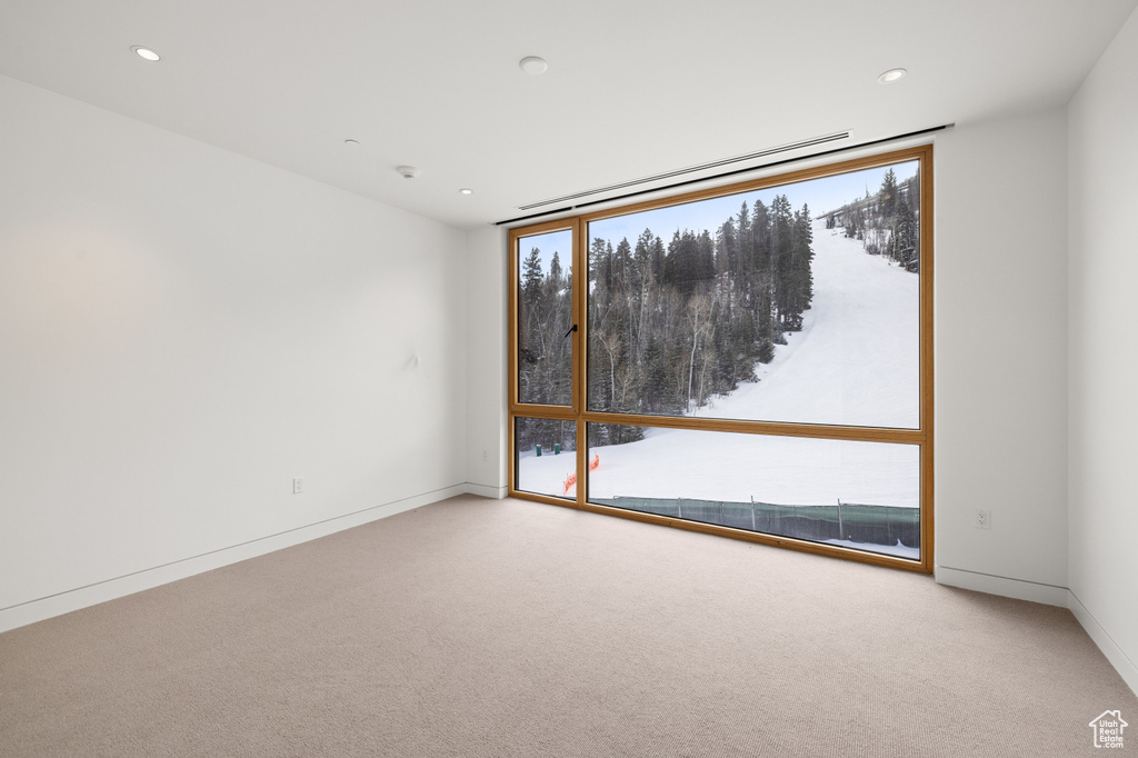 Carpeted spare room featuring recessed lighting, baseboards, and a wall of windows