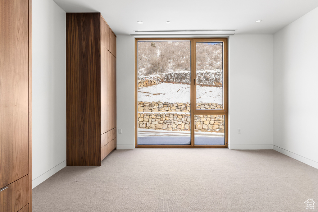 Unfurnished room featuring light colored carpet, recessed lighting, floor to ceiling windows, and baseboards