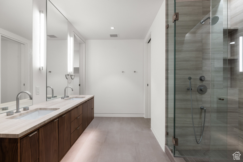 Full bathroom with a stall shower, double vanity, visible vents, and a sink