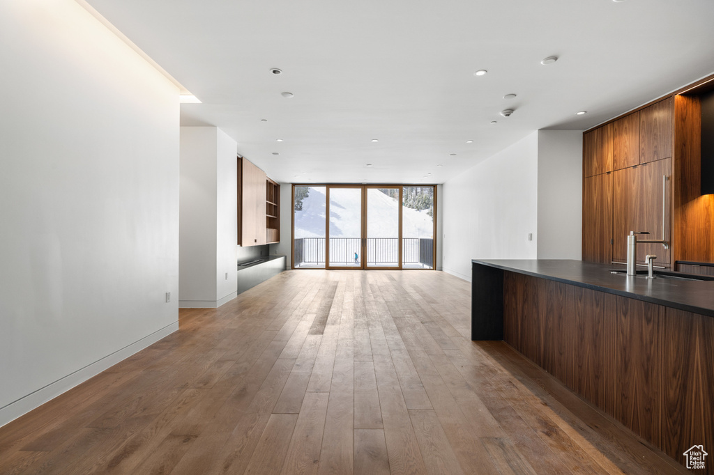 Kitchen featuring light wood finished floors, floor to ceiling windows, modern cabinets, dark countertops, and a sink