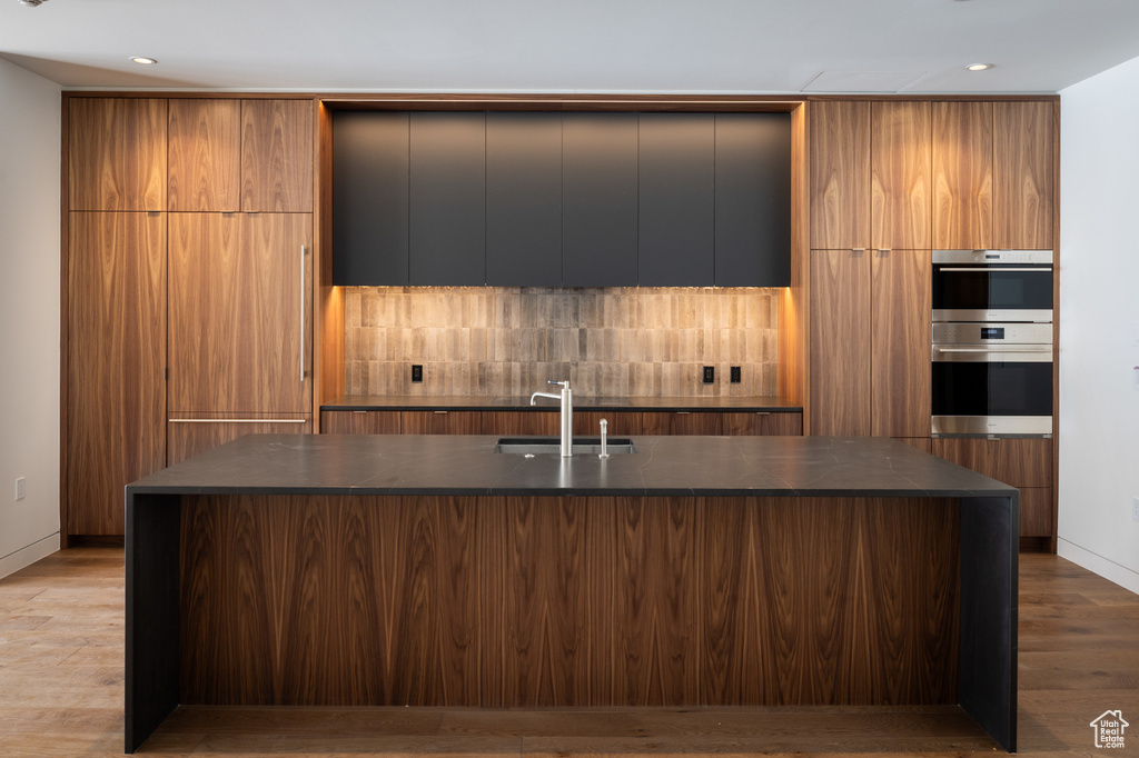 Kitchen with a sink, dark countertops, stainless steel double oven, and modern cabinets