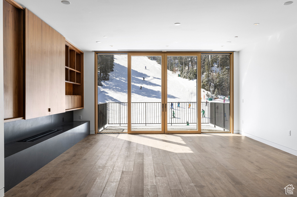 Unfurnished living room featuring baseboards, floor to ceiling windows, and wood finished floors