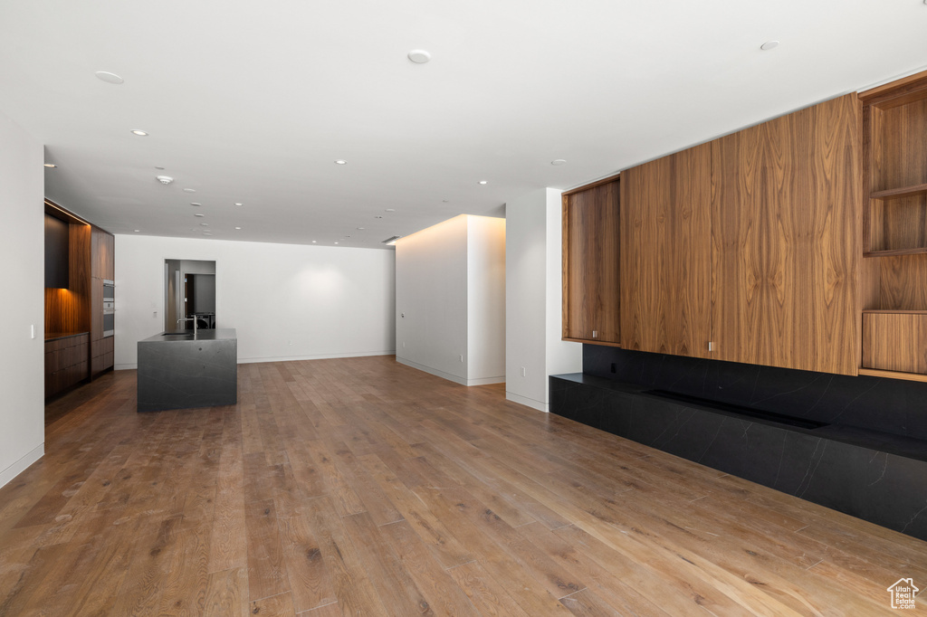 Unfurnished living room with baseboards, wood finished floors, and recessed lighting