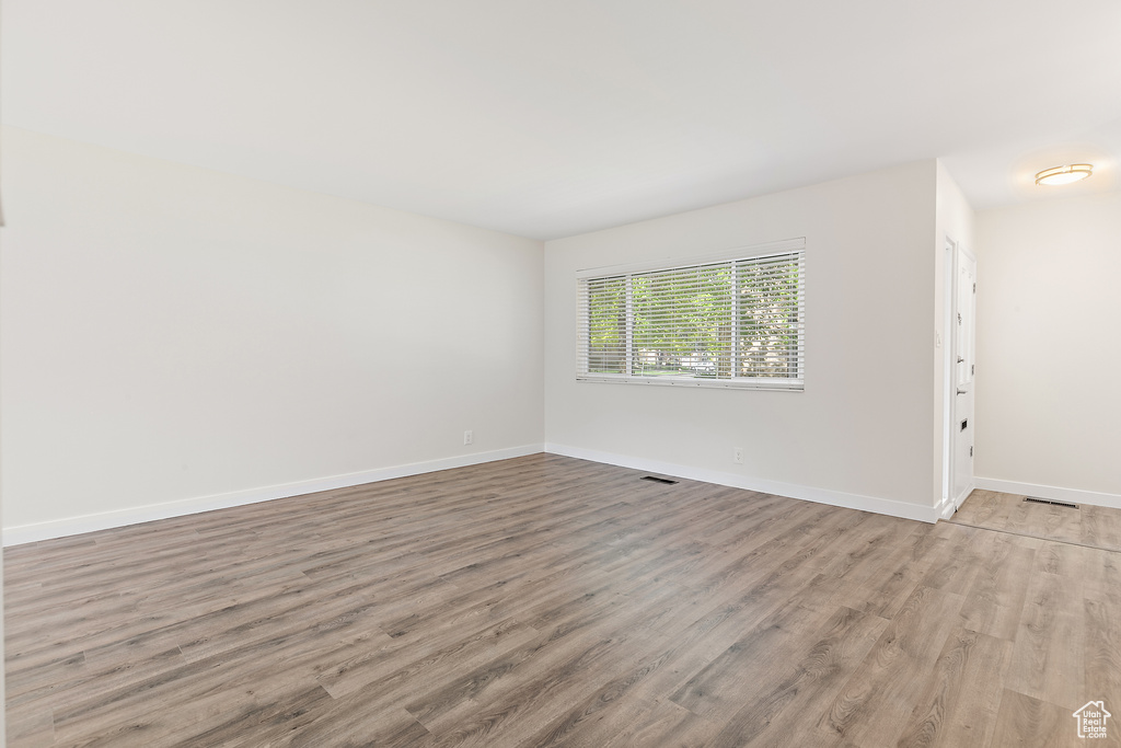 Unfurnished room featuring baseboards, visible vents, and light wood-style floors