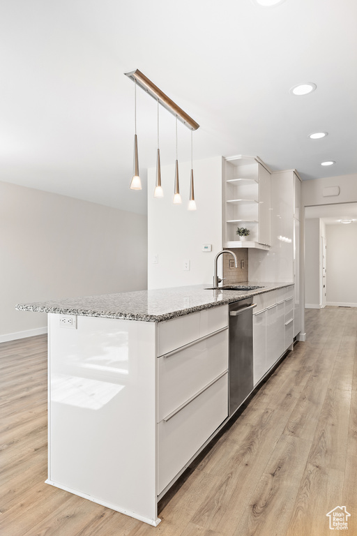 Kitchen with modern cabinets, open shelves, light wood-type flooring, dishwasher, and a sink