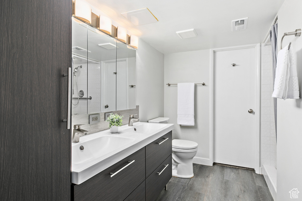 Bathroom featuring visible vents, a sink, wood finished floors, and a shower