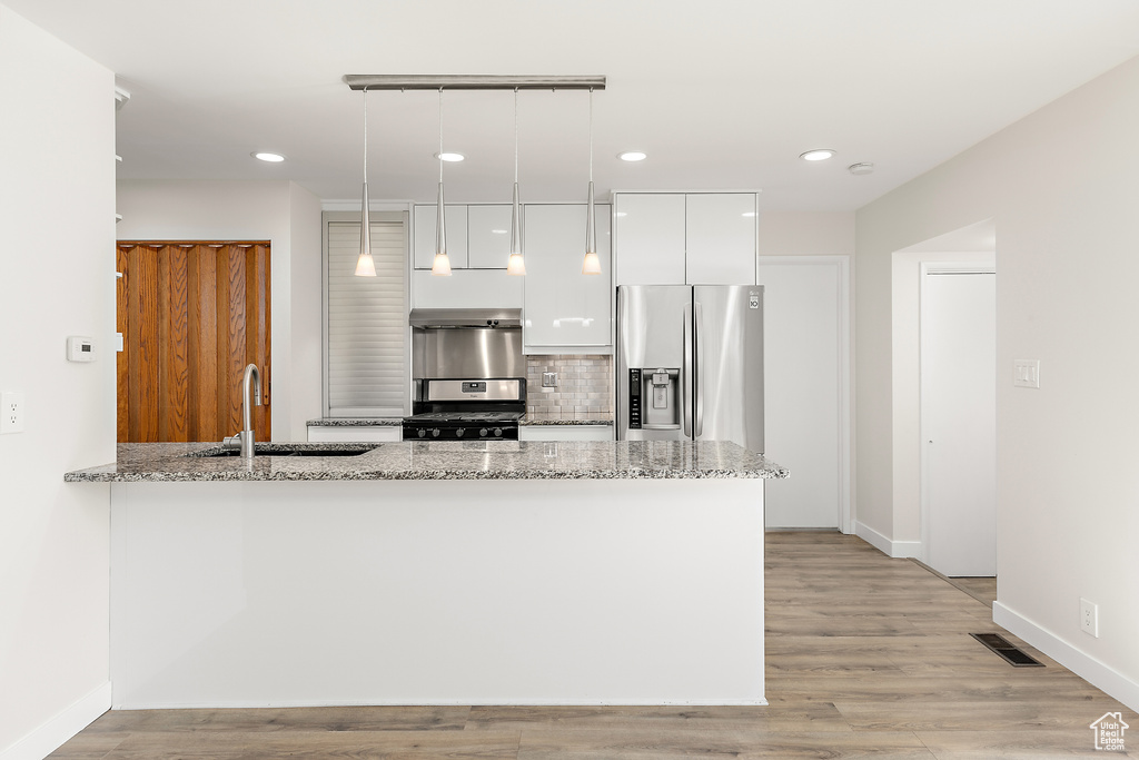Kitchen with a sink, stainless steel appliances, white cabinetry, a peninsula, and visible vents