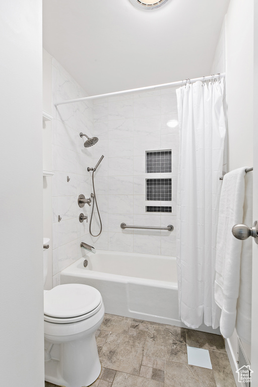 Full bath with toilet, shower / tub combo, and stone finish floor