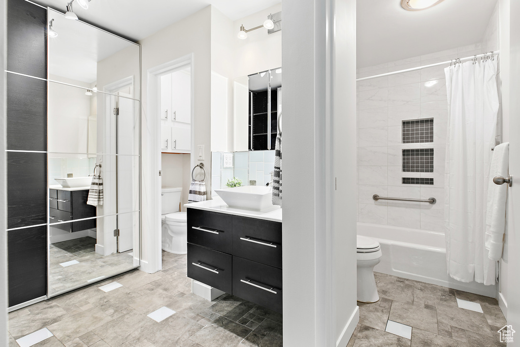 Full bath featuring toilet, shower / bath combination with curtain, and vanity