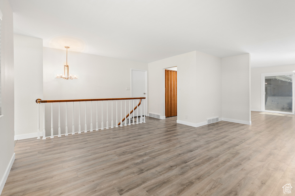 Spare room with a chandelier, baseboards, visible vents, and light wood finished floors