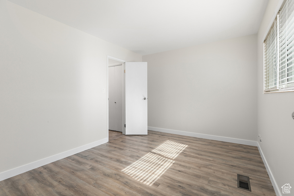 Unfurnished bedroom with baseboards, wood finished floors, and visible vents
