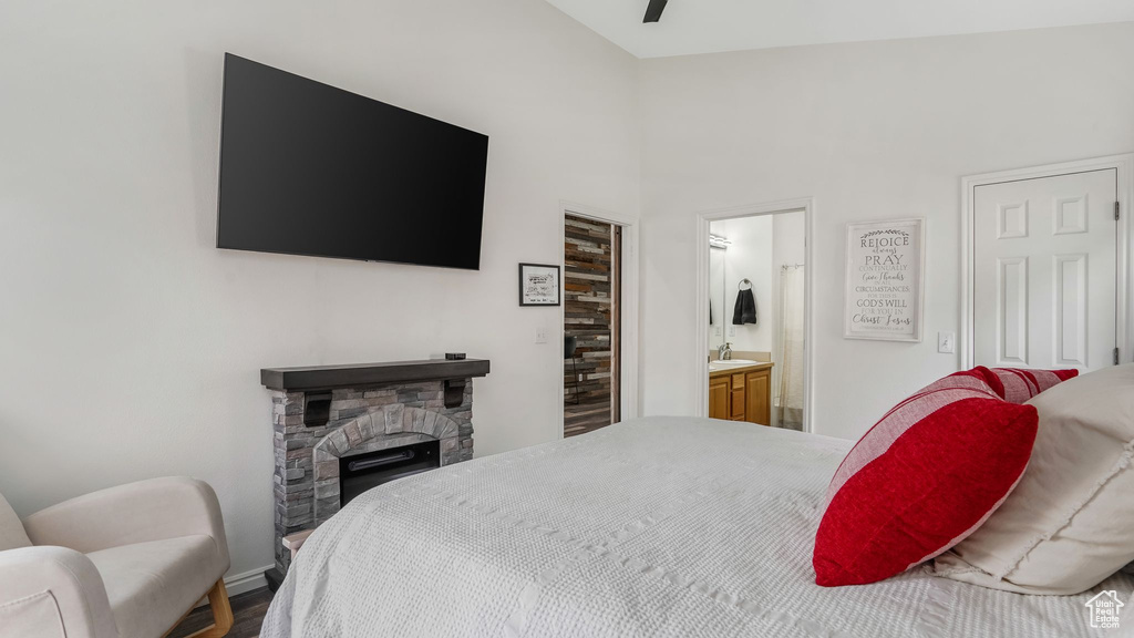 Bedroom featuring a stone fireplace, a sink, ensuite bath, and baseboards