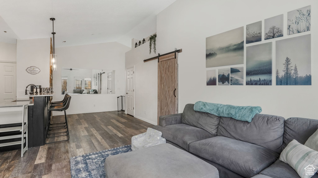 Living room with a barn door, dark wood-style floors, and high vaulted ceiling