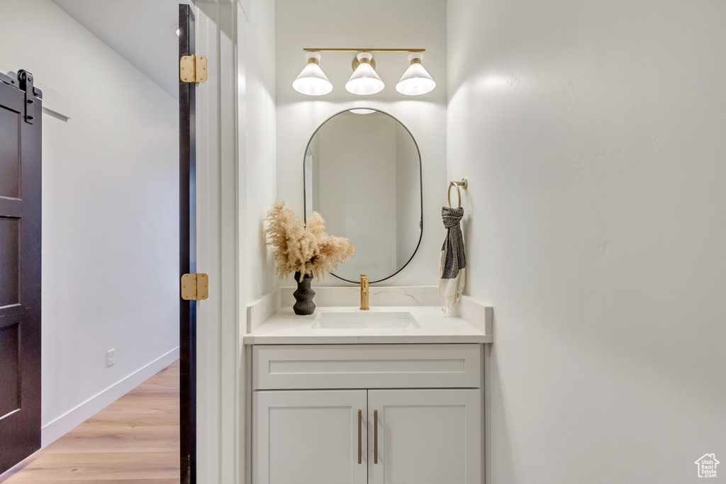 Bathroom with vanity, baseboards, and wood finished floors