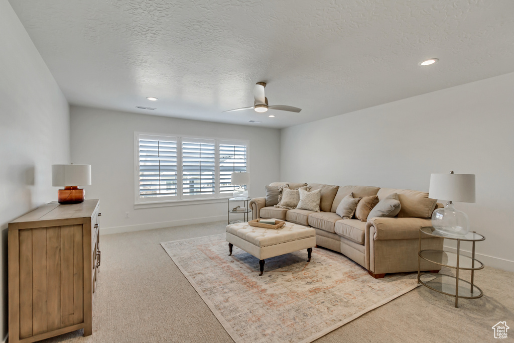 Living area with a ceiling fan, a textured ceiling, baseboards, light colored carpet, and recessed lighting