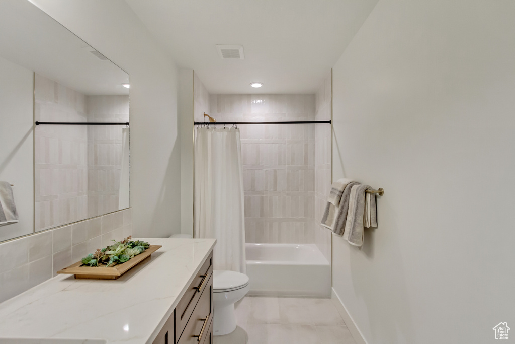 Full bathroom featuring toilet, vanity, shower / bath combo with shower curtain, baseboards, and visible vents