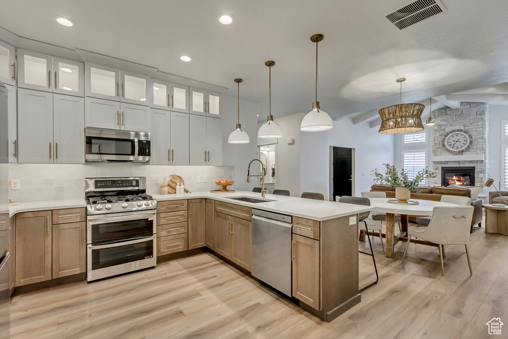 Kitchen featuring visible vents, light wood-style flooring, stainless steel appliances, tasteful backsplash, and a sink