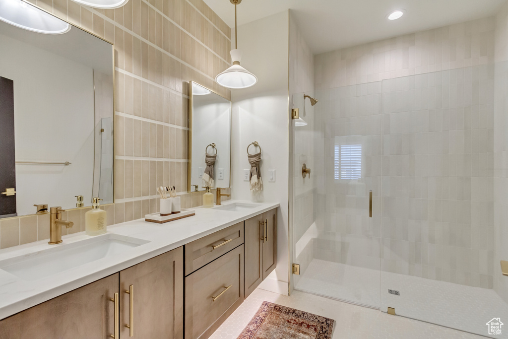 Bathroom with a stall shower, double vanity, tile patterned flooring, and a sink