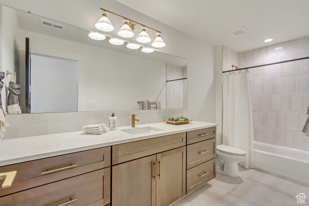 Full bath with vanity, tasteful backsplash, shower / tub combo, toilet, and visible vents