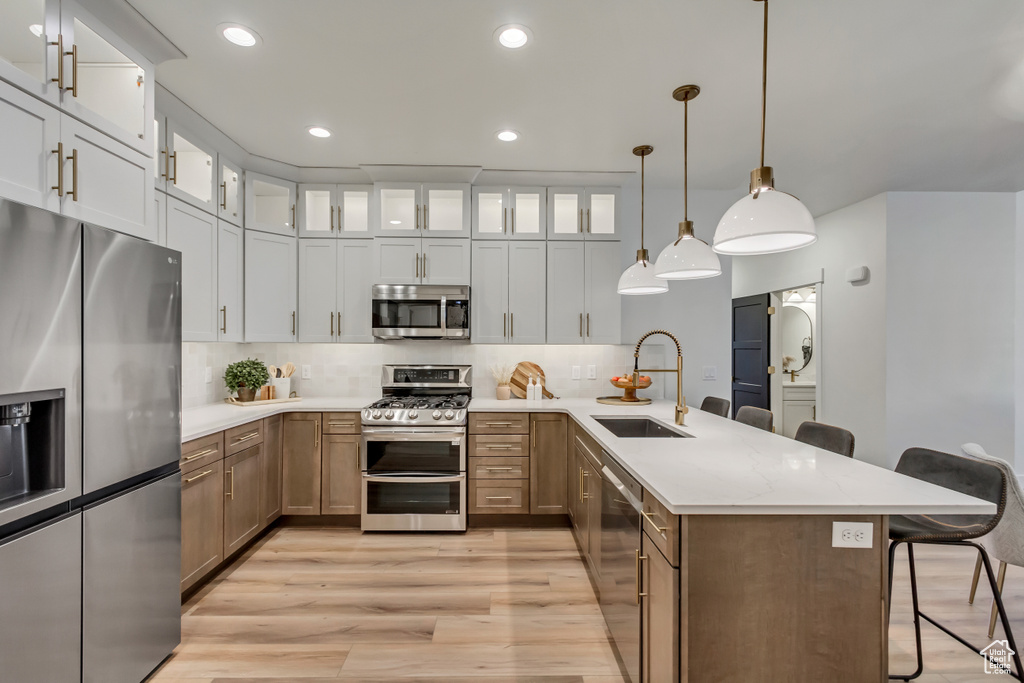 Kitchen featuring a sink, a breakfast bar area, a peninsula, stainless steel appliances, and decorative backsplash