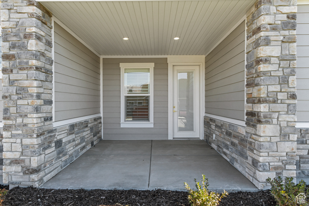 Entrance to property with stone siding and a patio