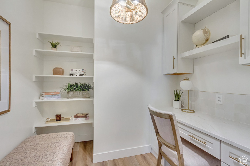 Home office with light wood finished floors, baseboards, and an inviting chandelier