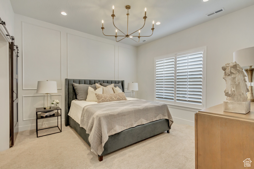 Bedroom with a decorative wall, light colored carpet, visible vents, recessed lighting, and an inviting chandelier