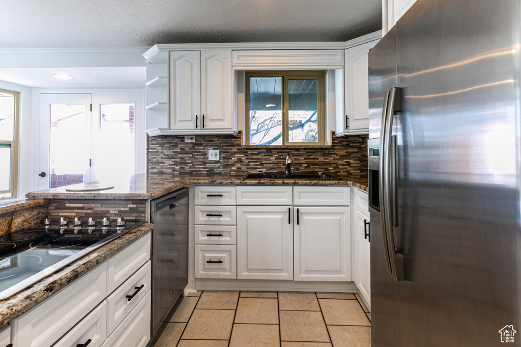 Kitchen featuring a sink, white cabinetry, black appliances, and tasteful backsplash