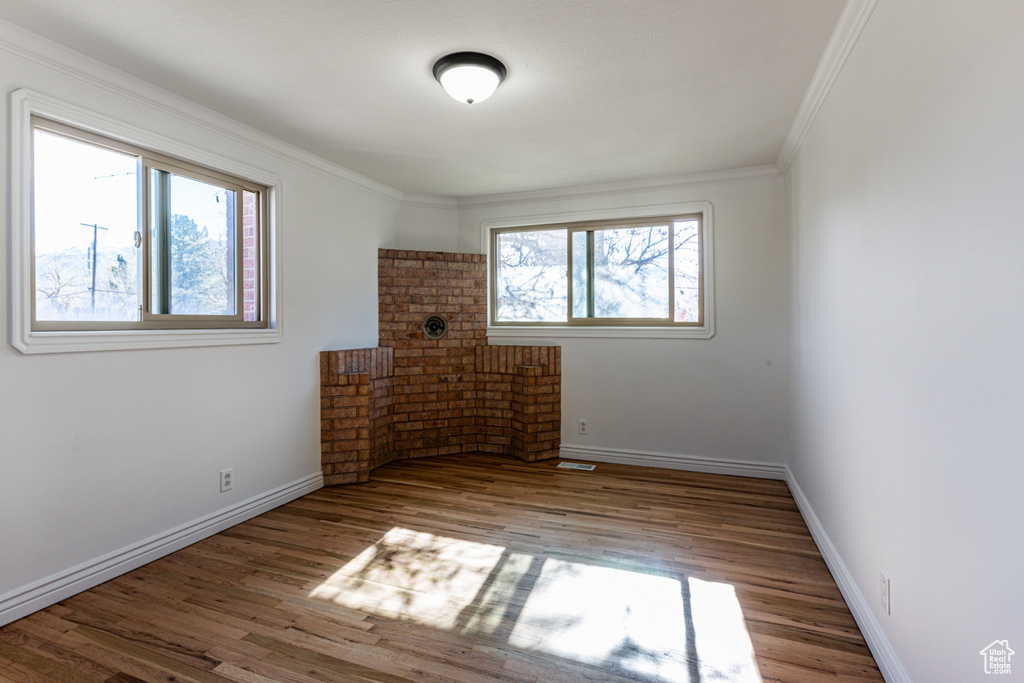 Unfurnished room featuring baseboards, ornamental molding, and wood finished floors