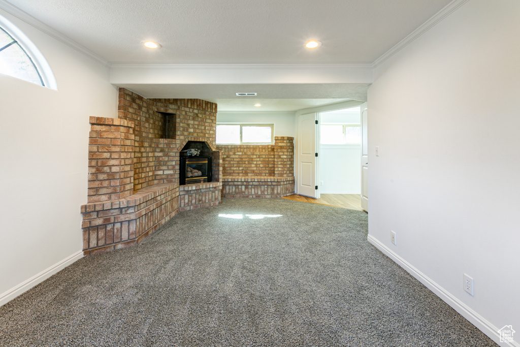 Unfurnished living room with carpet, crown molding, a fireplace, baseboards, and recessed lighting