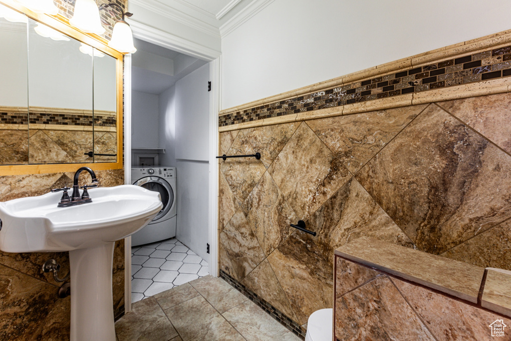 Bathroom with tile patterned floors, crown molding, washer / clothes dryer, and tile walls