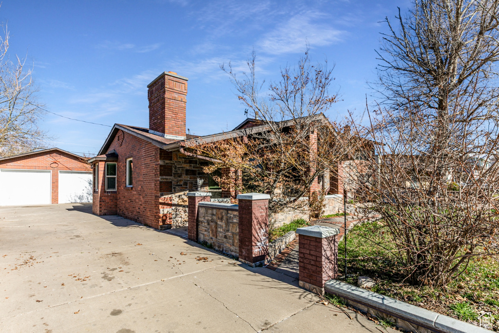View of home\'s exterior featuring fence, a chimney, a detached garage, brick siding, and an outdoor structure