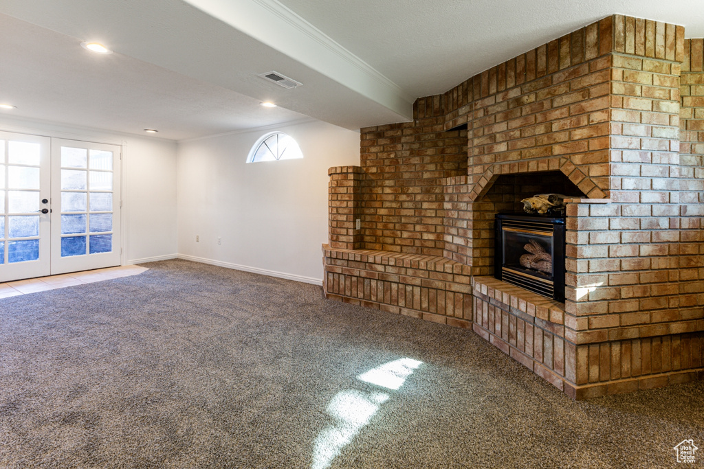 Unfurnished living room featuring carpet flooring, visible vents, a brick fireplace, baseboards, and recessed lighting