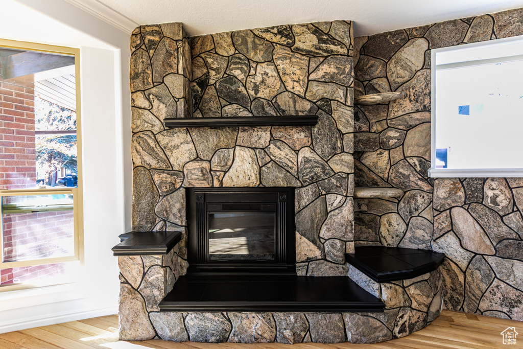 Details featuring a stone fireplace, crown molding, a textured ceiling, and wood finished floors