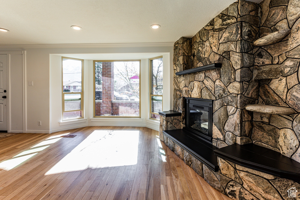 Unfurnished living room featuring crown molding, a fireplace, wood finished floors, baseboards, and recessed lighting