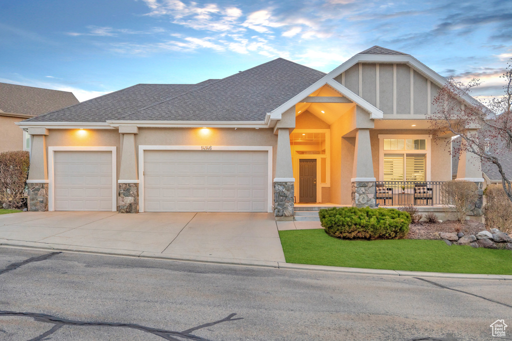 Craftsman inspired home with stone siding, an attached garage, stucco siding, and driveway