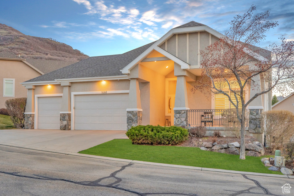 View of front of home featuring stone siding, a garage, driveway, and stucco siding