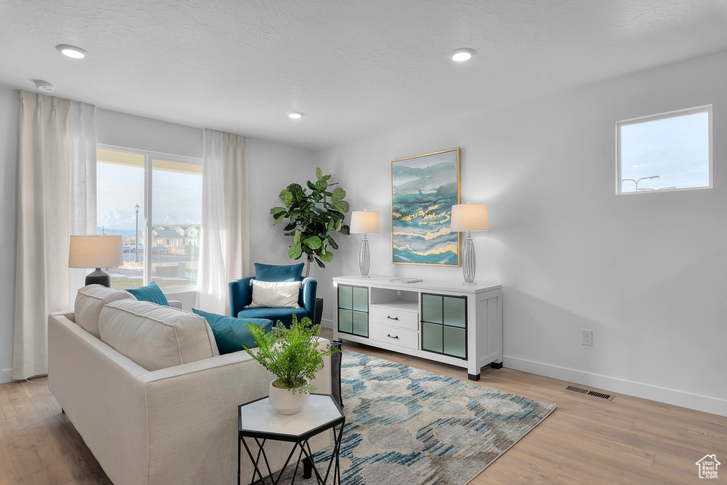 Living room featuring recessed lighting, baseboards, a textured ceiling, light wood-style floors, and visible vents