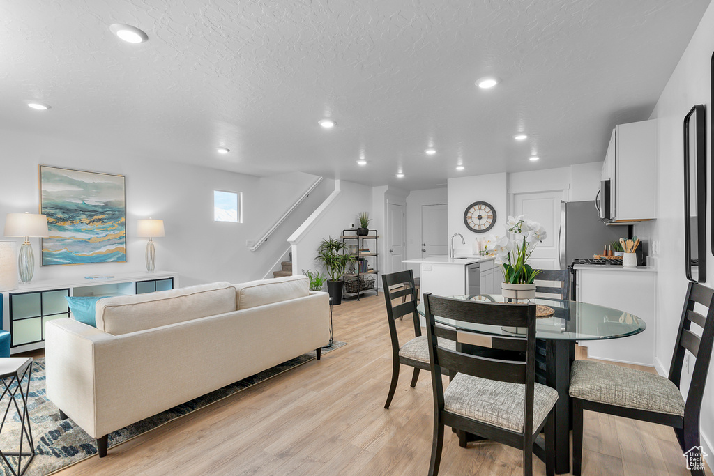 Dining room with a textured ceiling, recessed lighting, stairway, and light wood finished floors
