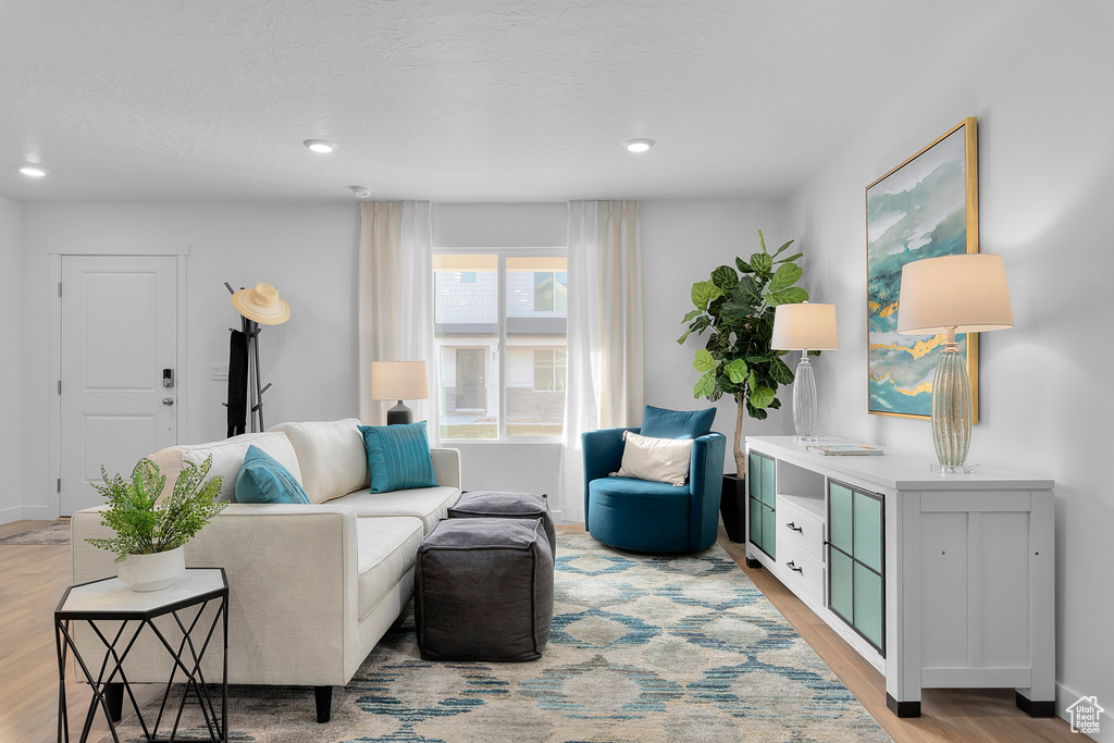 Living room featuring baseboards, light wood-style floors, recessed lighting, and a textured ceiling
