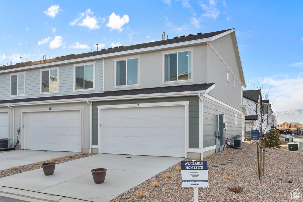 View of property with driveway, cooling unit, and a garage