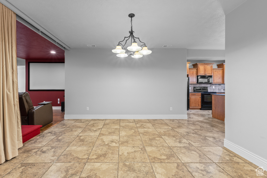 Unfurnished dining area with a chandelier and baseboards